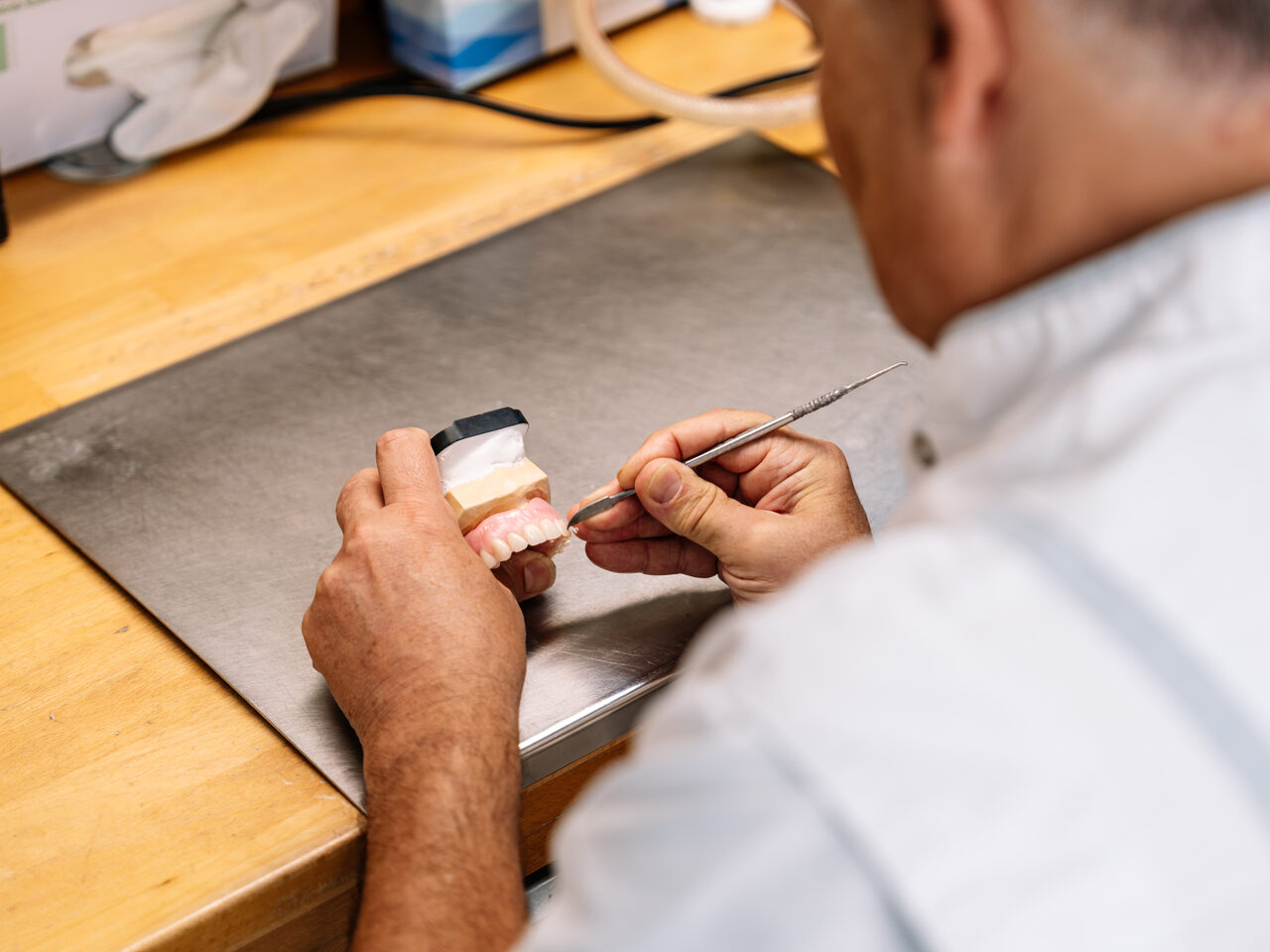 Tandtechnicus voert een spoedreparatie uit aan een prothese op een gipsmodel